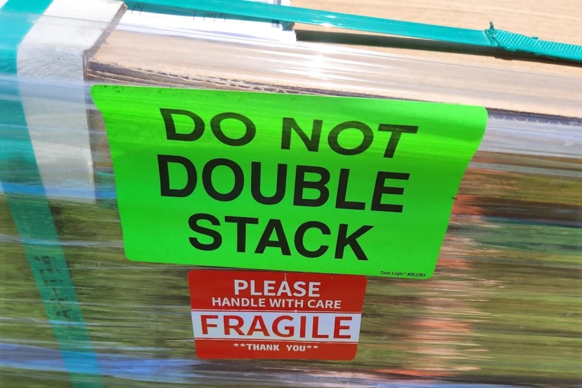 Bright warning labels state "DO NOT DOUBLE STACK" and "PLEASE HANDLE WITH CARE FRAGILE" on a wrapped shipment.