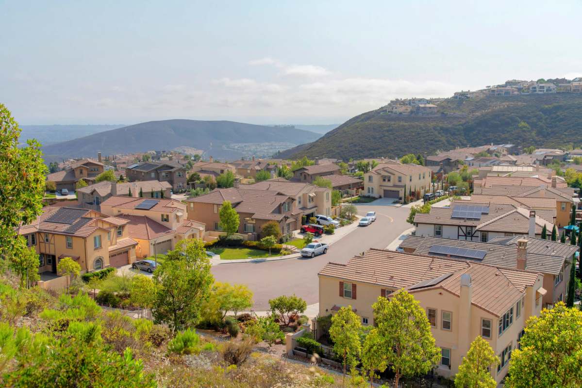A panoramic view of a suburban neighborhood with houses nestled among rolling hills.