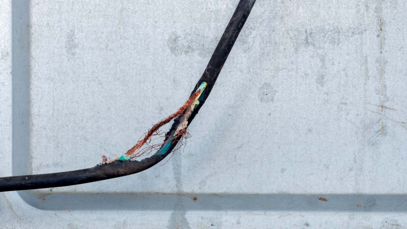 A damaged electrical cable with exposed copper.