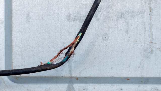A damaged electrical cable with exposed copper.