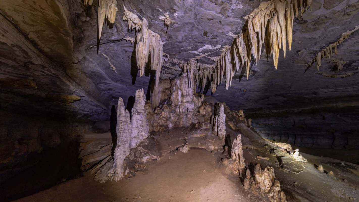 A dimly lit cave interior with stalagmites and stalactites.