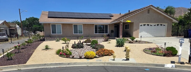 A drought-tolerant garden in front of a home with solar panels.