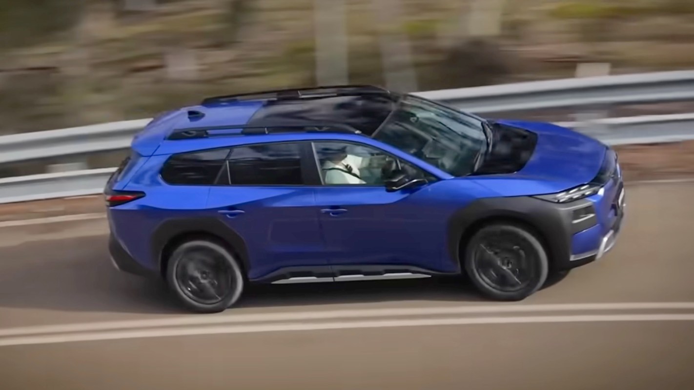 A blue SUV driving on a winding road with a blurred background, suggesting motion.