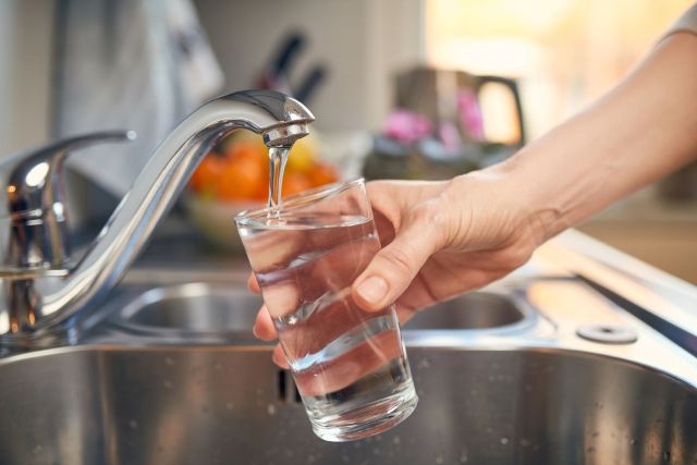 A person filling a glass with tap water.