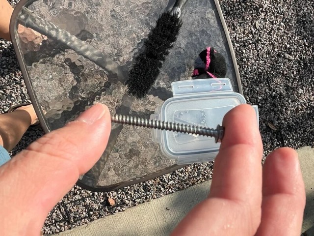 A hand holding a large screw.