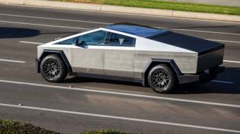 A silver Tesla Cybertruck drives on a road.