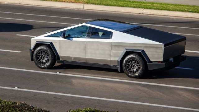 A silver Tesla Cybertruck drives on a road.
