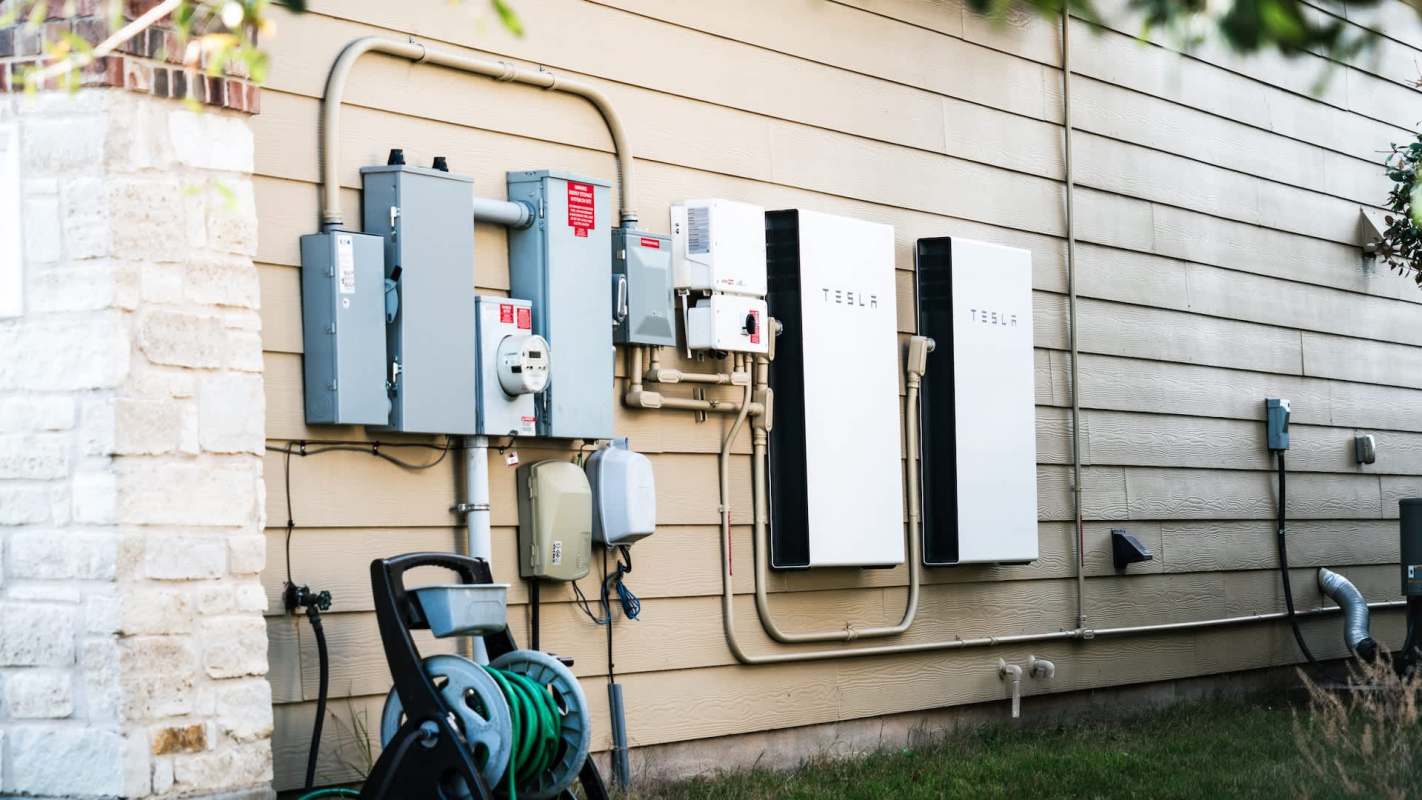 A side view of an exterior wall featuring electrical panels and Tesla energy storage units.