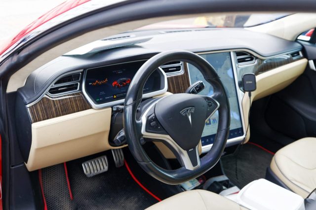 A modern car interior featuring a sleek dashboard, touchscreen display, and plush seating in a Tesla vehicle.