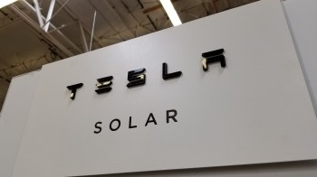 A sign displaying the Tesla logo with the word "SOLAR" underneath in a modern font.