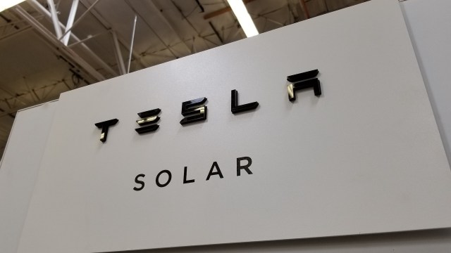 A sign displaying the Tesla logo with the word "SOLAR" underneath in a modern font.