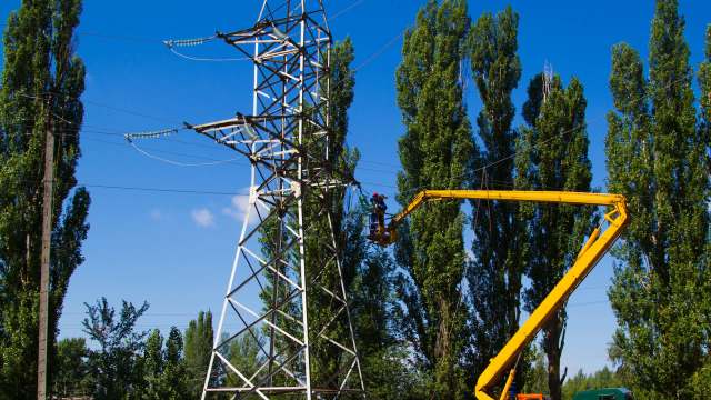 A worker repairing a power line from a cherry picker.
