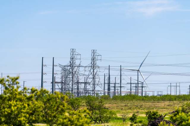 Wind turbines near power lines and electrical towers.