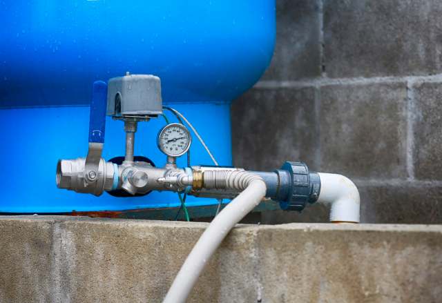 A water pump system with a pressure gauge and blue tank.
