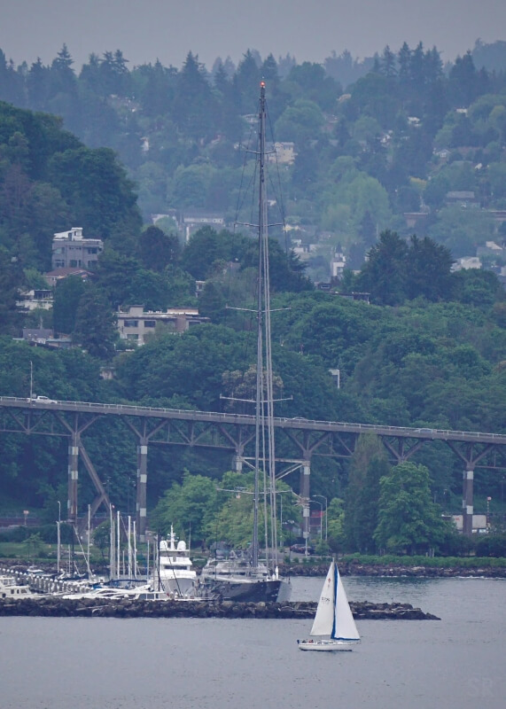 A large yacht with an enormous mast in a harbor.