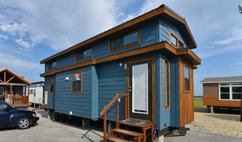 A blue tiny house with wooden accents.