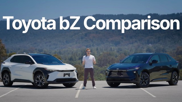 A presenter stands between two Toyota bZ electric vehicles in a parking lot with mountains in the background.