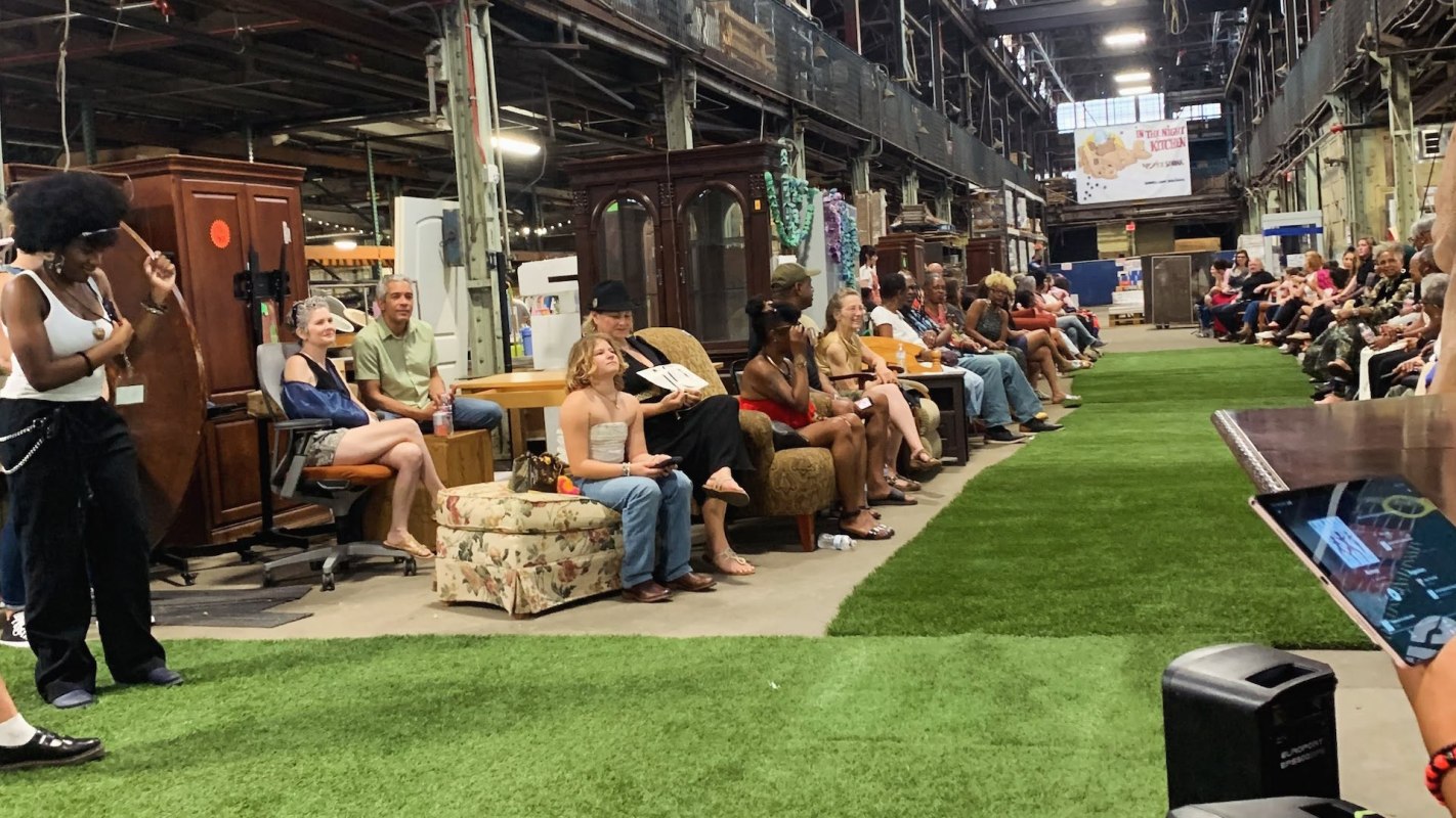 Spectators seated around an artificial turf runway at the Trashion Show.