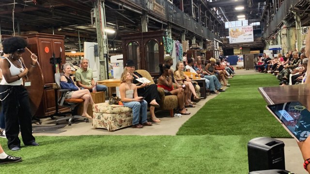 Spectators seated around an artificial turf runway at the Trashion Show.