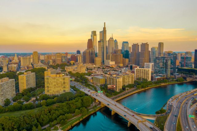 Aerial view of a city skyline at sunset with tall buildings and a winding river.