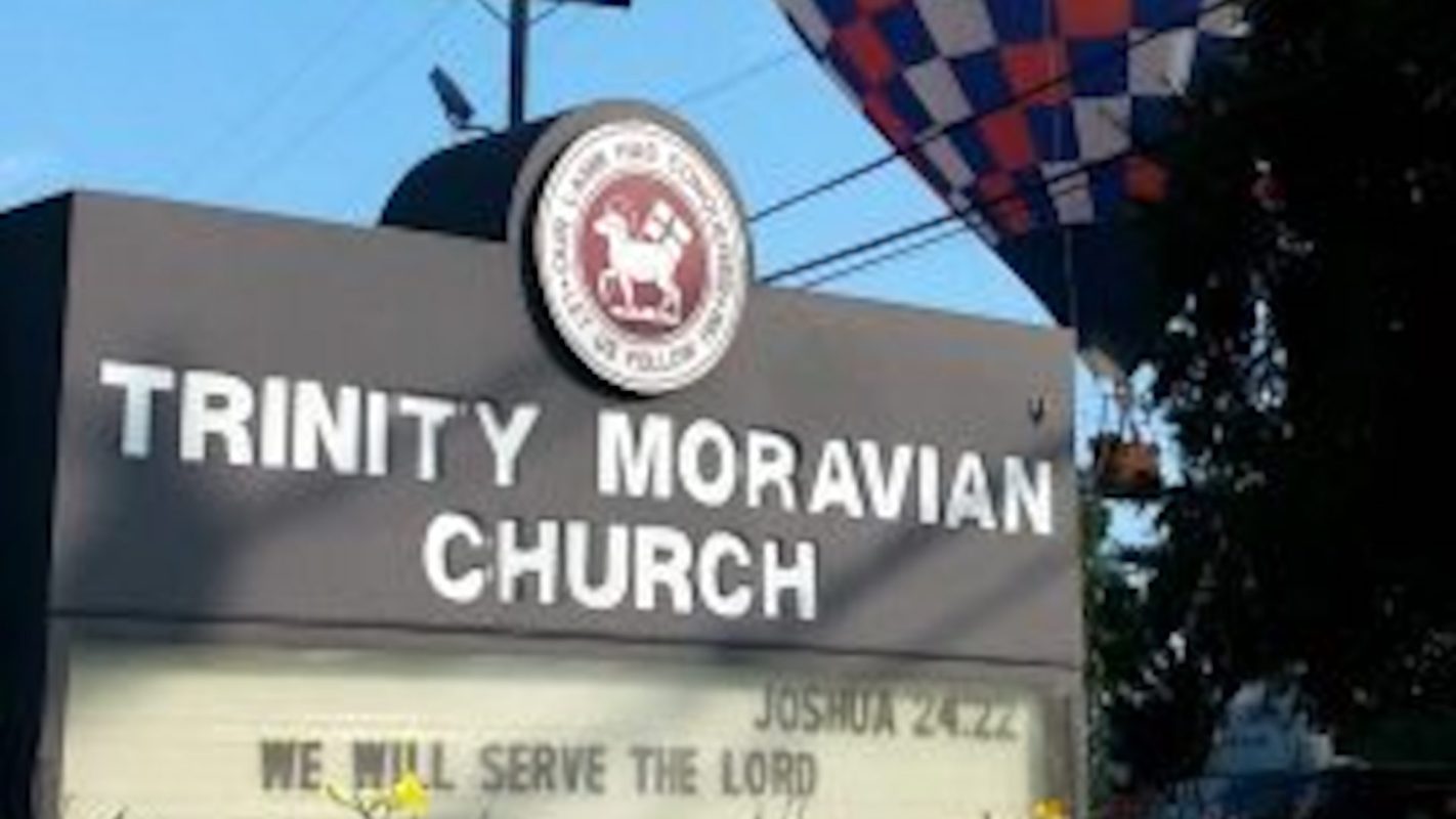 A sign for Trinity Moravian Church referencing Joshua 24:22.