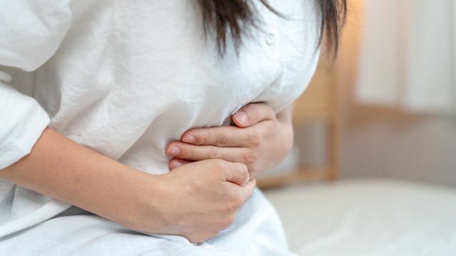 A person holds their stomach in discomfort.