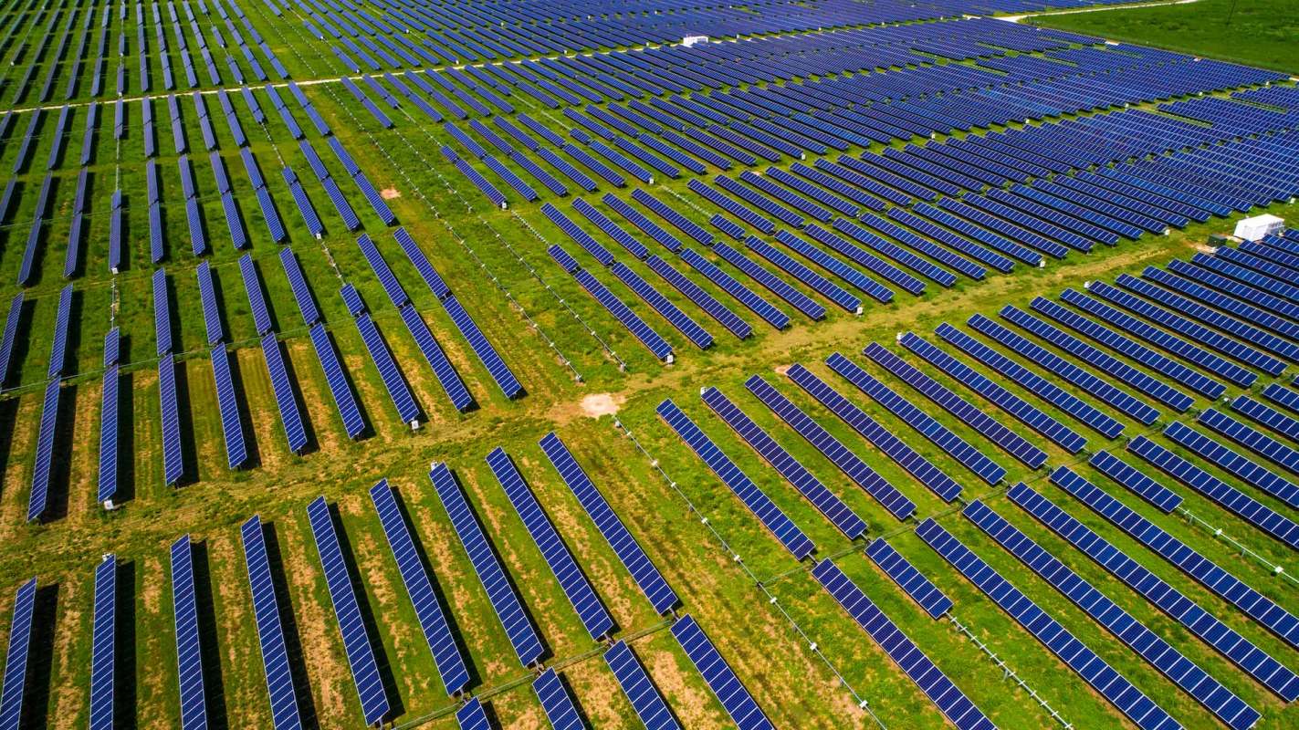 Aerial view of a large solar farm on grass.