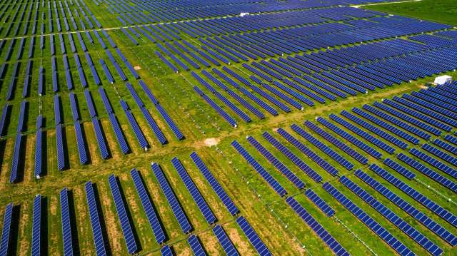 Aerial view of a large solar farm on grass.
