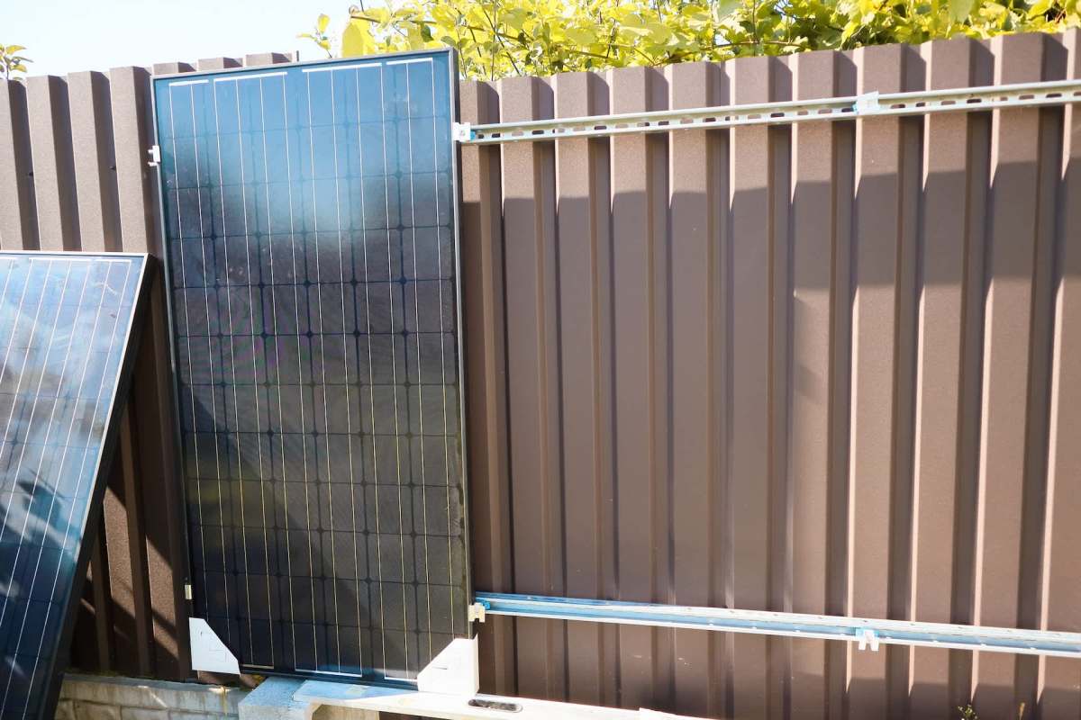 A solar panel mounted on a metal fence.