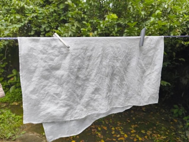 A cloth hung on a line with two pen lids holding it in place.