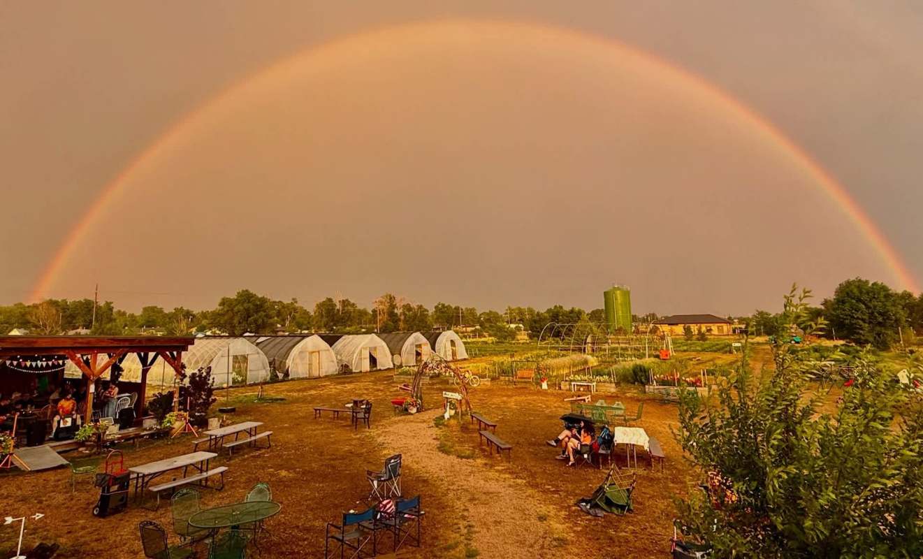 A rainbow over a farm with greenhouses.