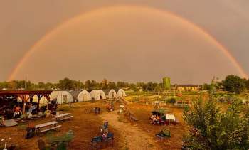 A rainbow over a farm with greenhouses.