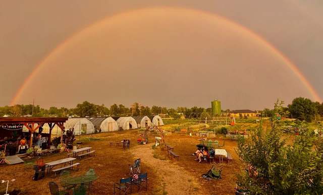 A rainbow over a farm with greenhouses.