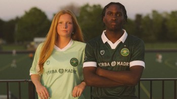 A male and female soccer player pose confidently in team jerseys, with a green field in the background.