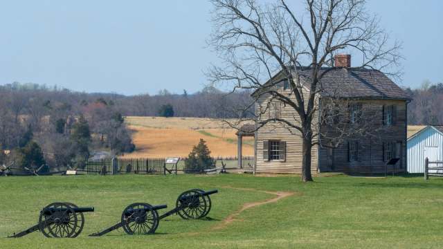 A historic house with cannons on its expansive rural yard.