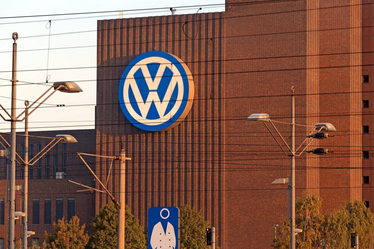 A large Volkswagen logo is displayed on a brick building, surrounded by power lines and streetlights.