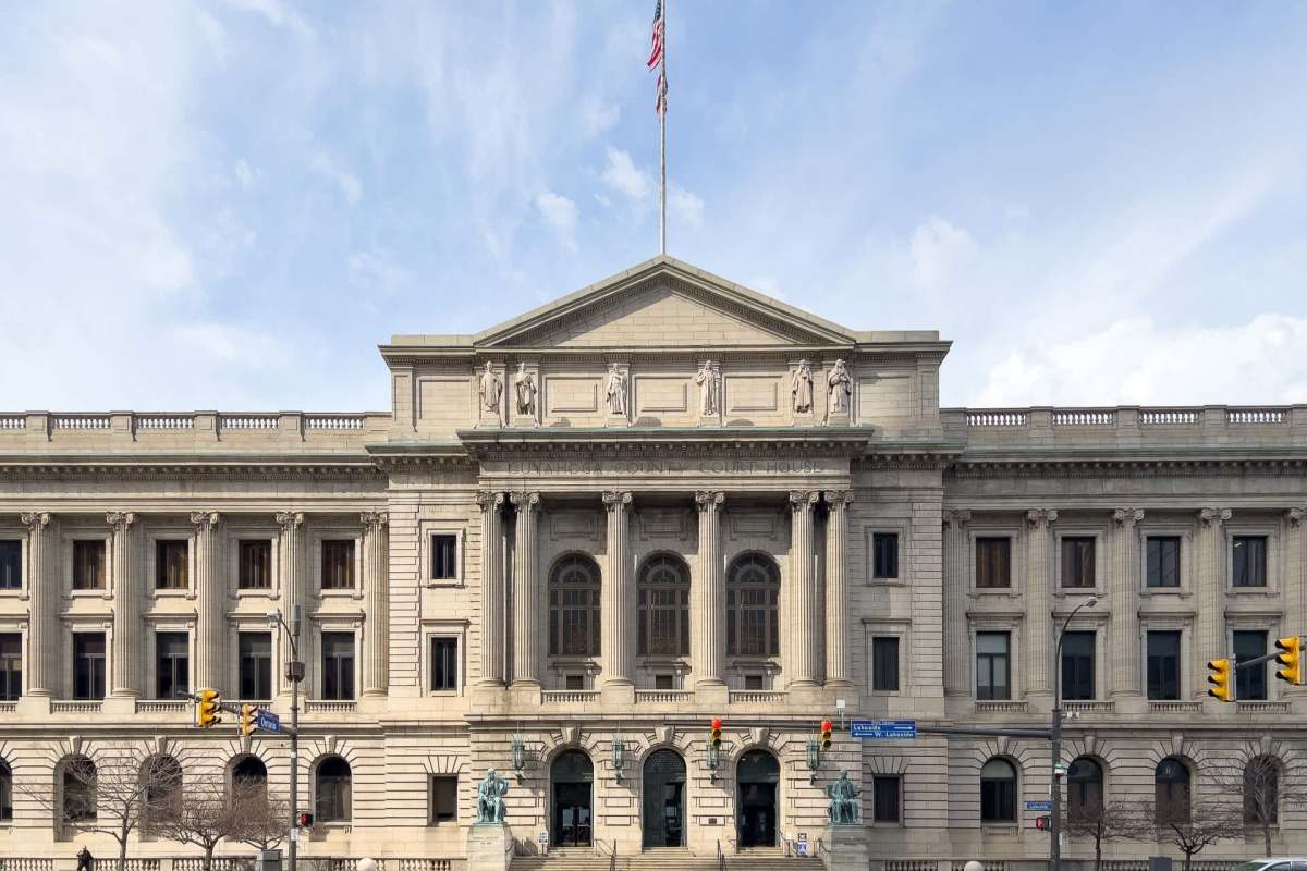A grand courthouse building with classical architecture, featuring statues and an American flag.