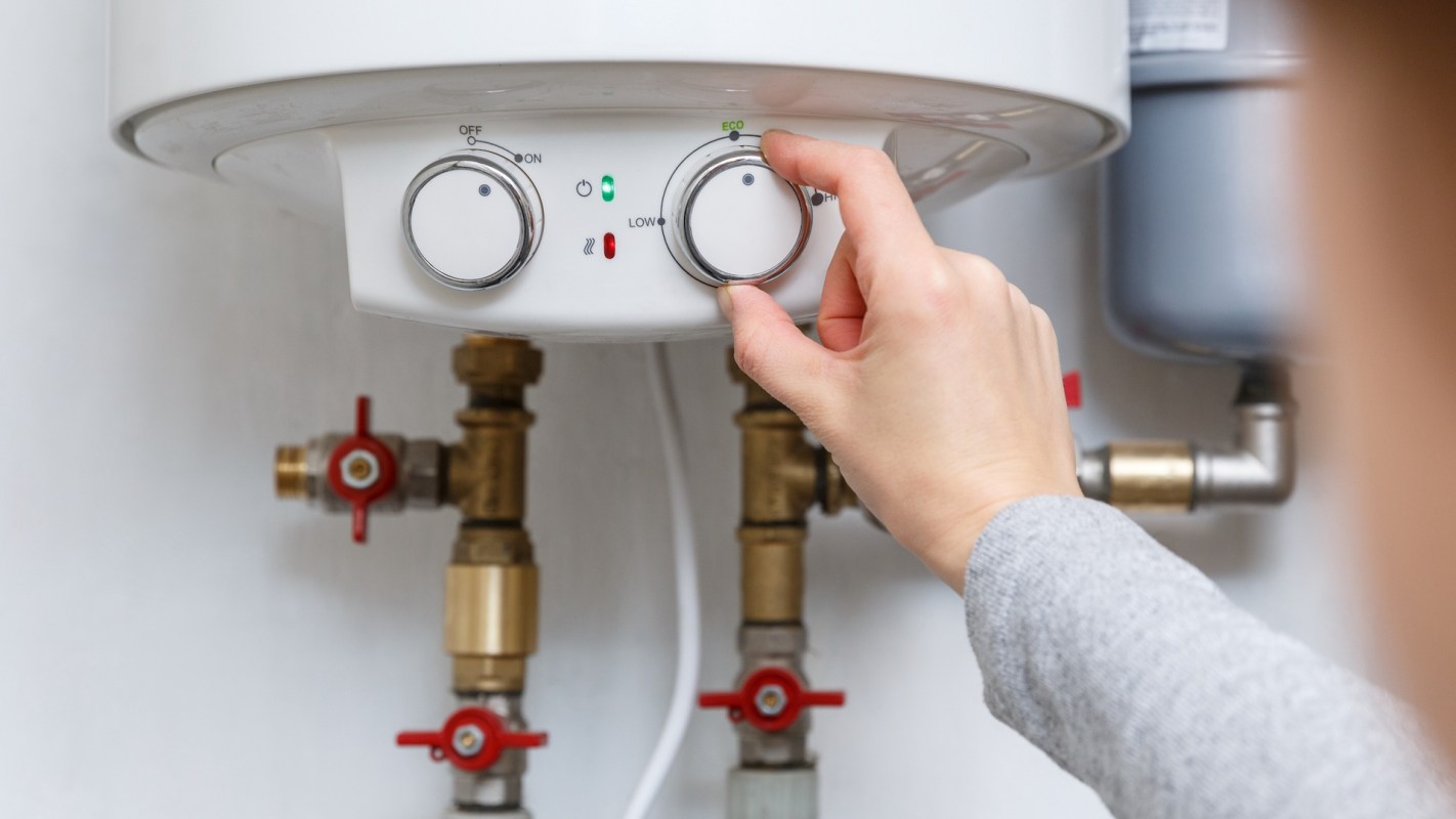 A person adjusting the controls on a water heater.