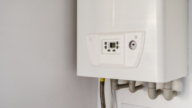 A white wall-mounted heating unit with a digital display and temperature gauge.