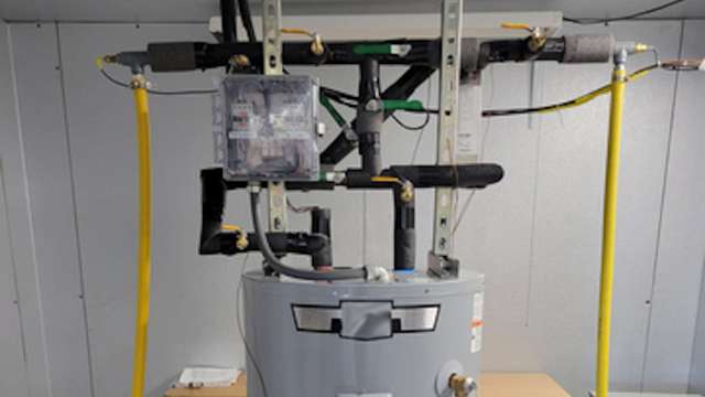 A water heater with connected pipes and a control panel mounted on a wall.