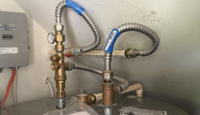 A close-up view of plumbing connections and valves near a water heater.