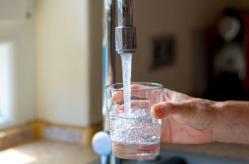 A person filling a glass with water.