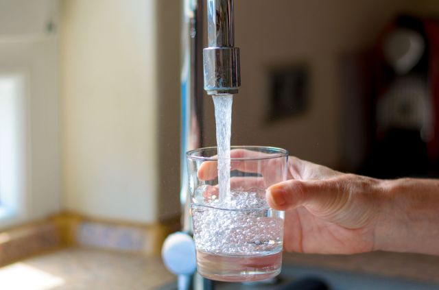 A person filling a glass with water.