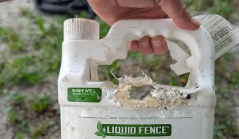 A person holding a damaged container of Liquid Fence.