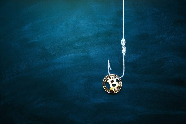 A Bitcoin coin is hanging from a fishing hook against a dark blue background.