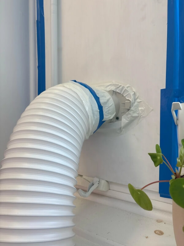 An AC exhaust hose connected to a wall.