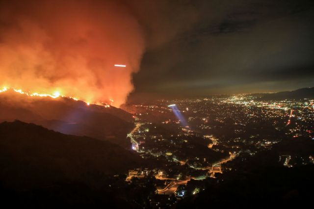 A wildfire burning above a city.
