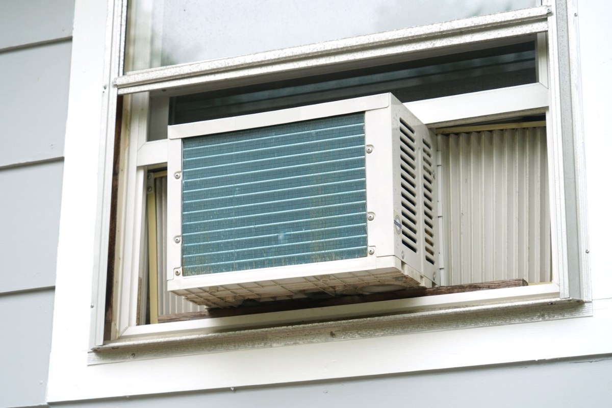 A window air conditioning unit installed in a house with gray siding.