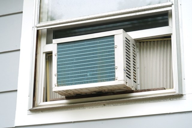 A window air conditioning unit installed in a house with gray siding.