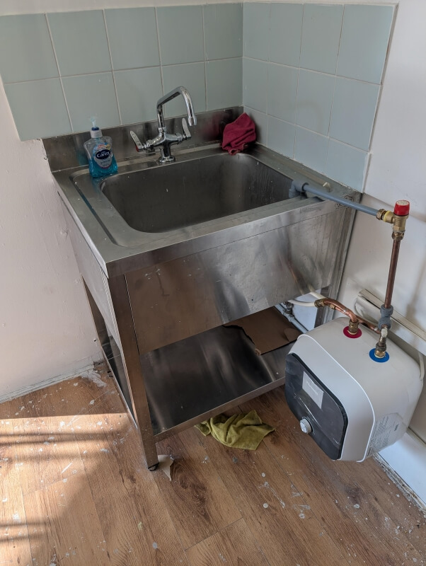 An under-the-sink water heater with a pipe extending into the sink. 